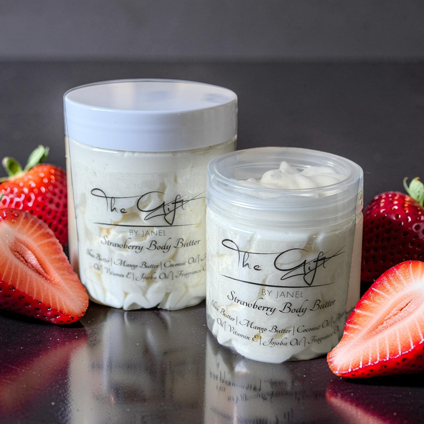 Two containers of strawberry body butter with strawberries on a dark surface