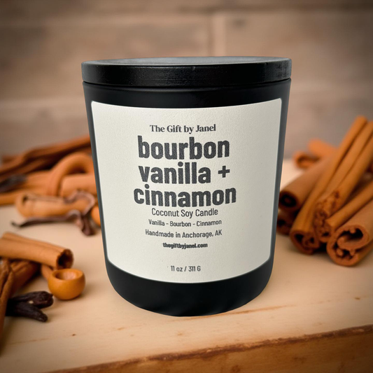 Candle labeled 'bourbon vanilla + cinnamon' with cinnamon sticks on a wooden surface