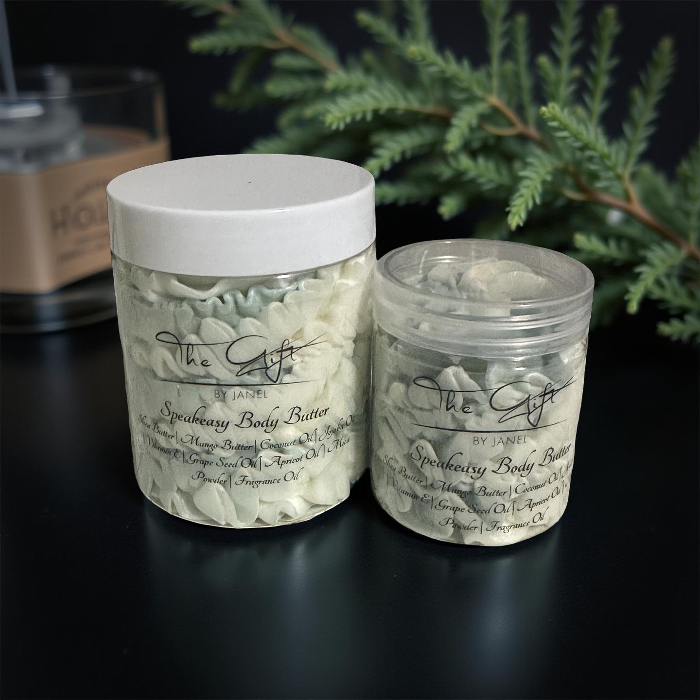 Two jars of SpeakeasyBody Butter on a dark surface with Cypress in the background