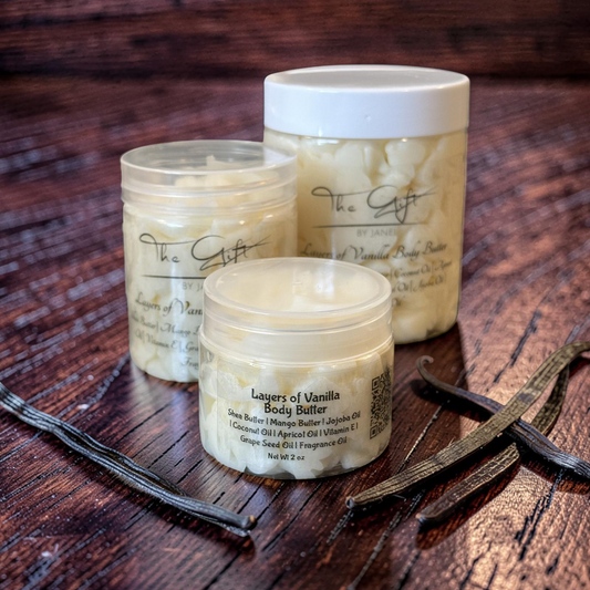 Three containers of 'Layers of Vanilla' body butter on a wooden surface with vanilla beans.