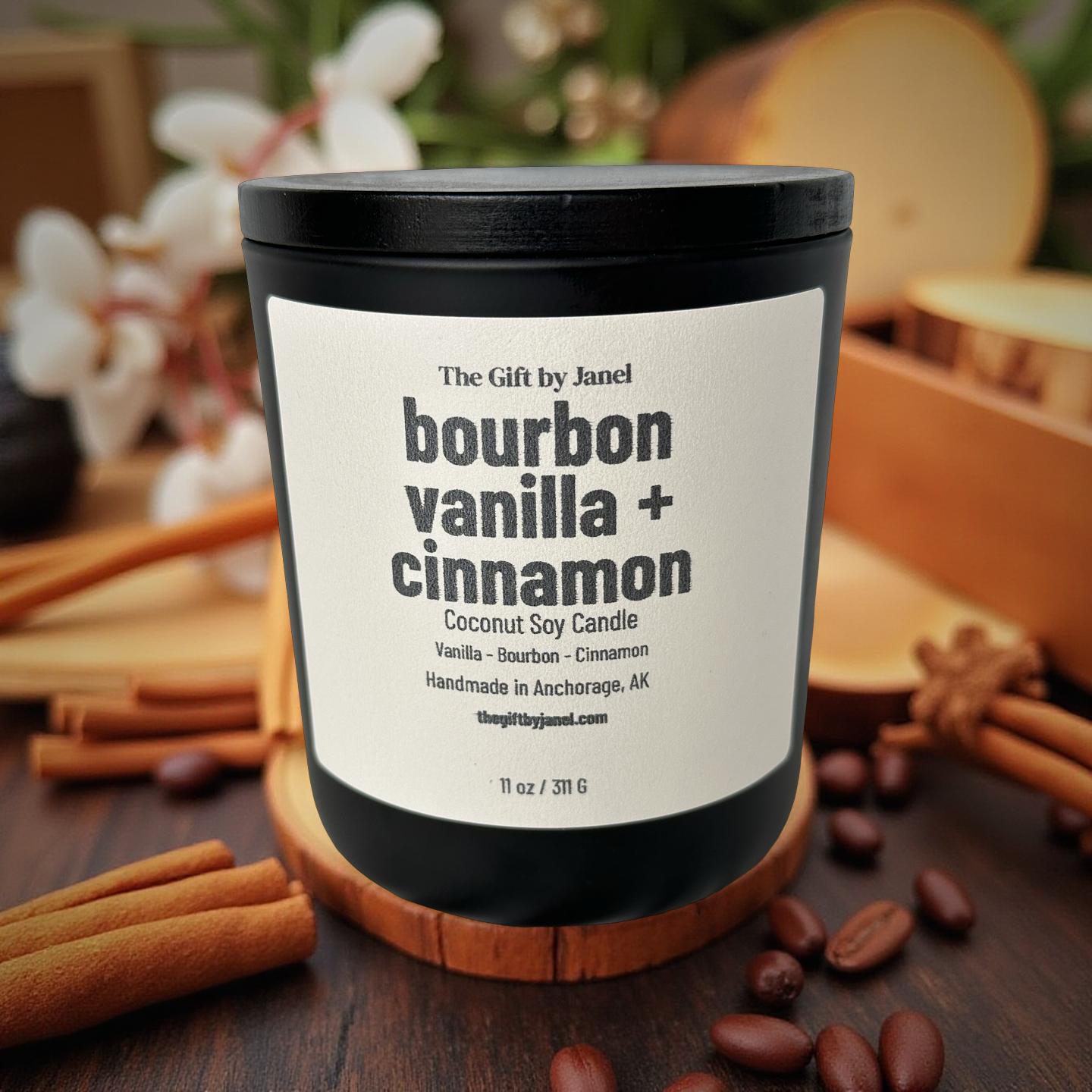 Candle labeled 'bourbon vanilla + cinnamon' on a wooden coaster with cinnamon sticks and beans.