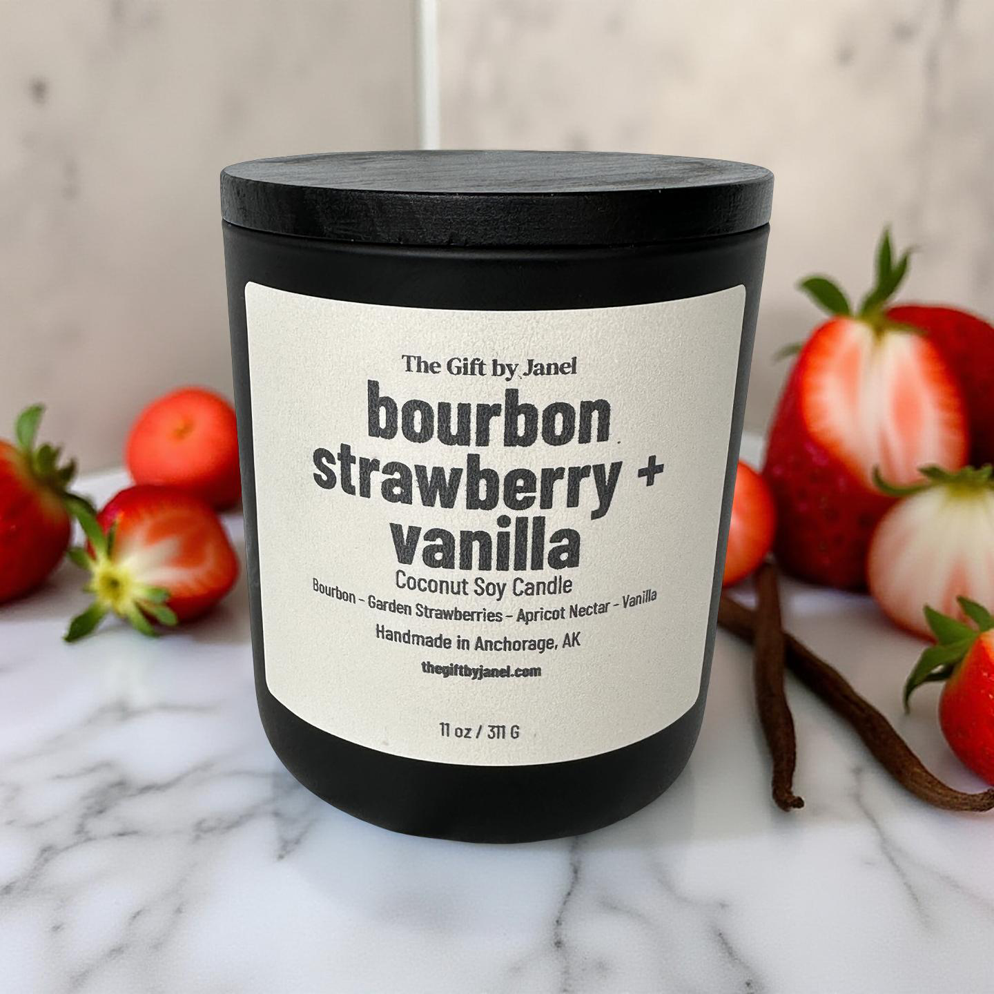 Candle labeled 'bourbon strawberry + vanilla' with strawberries and vanilla beans on a marble surface