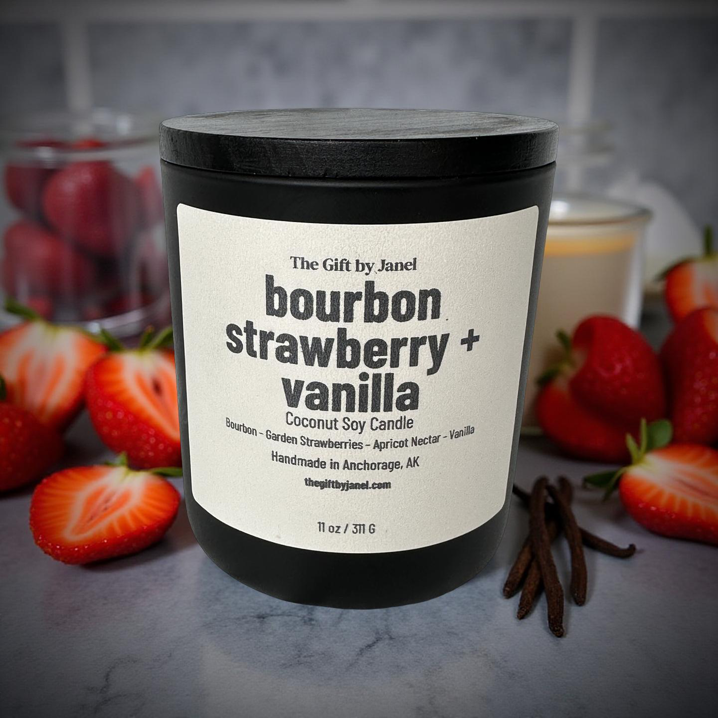 Candle with a bourbon strawberry vanilla scent surrounded by strawberries and vanilla beans on a marble surface.