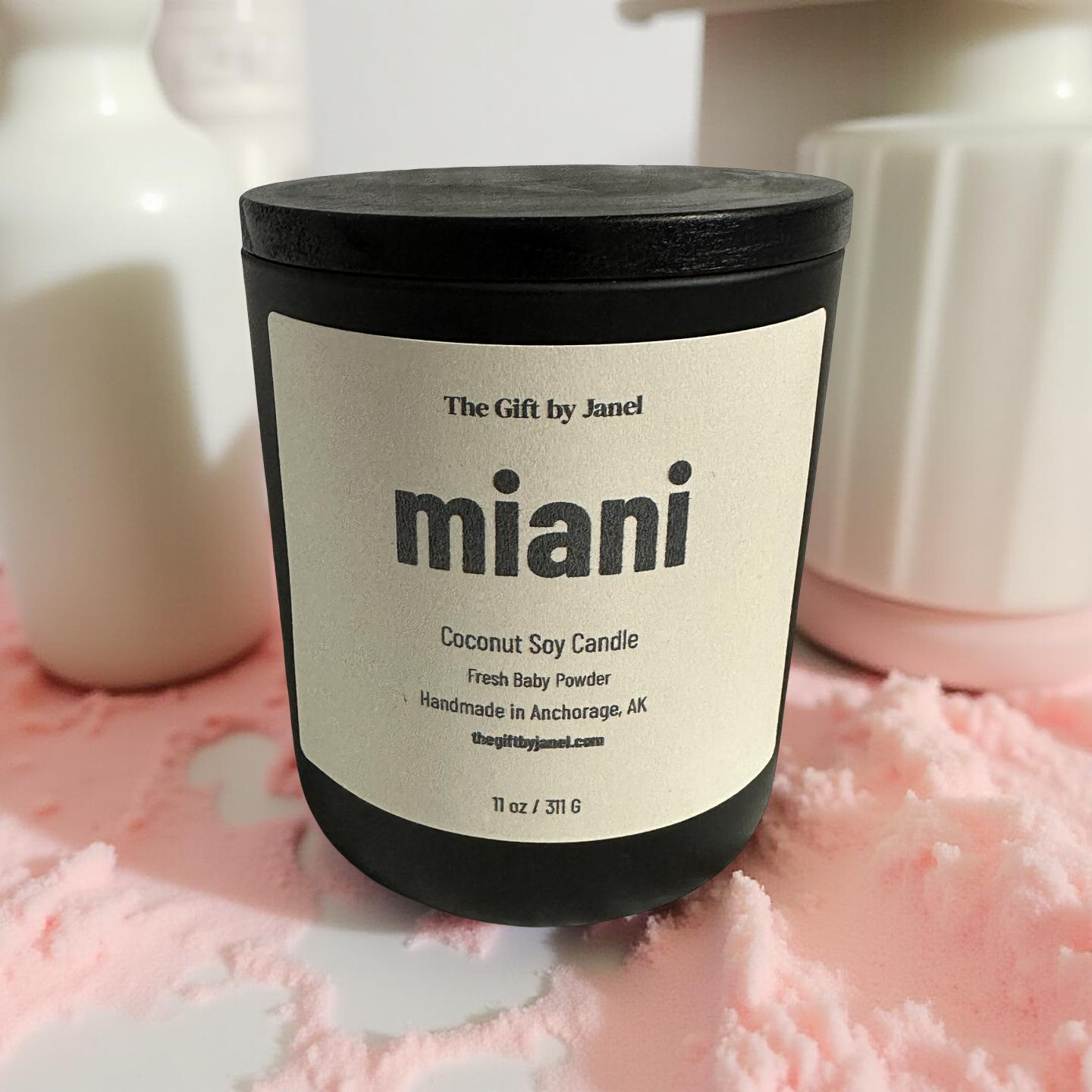Candle with 'miani' branding on a pink textured surface