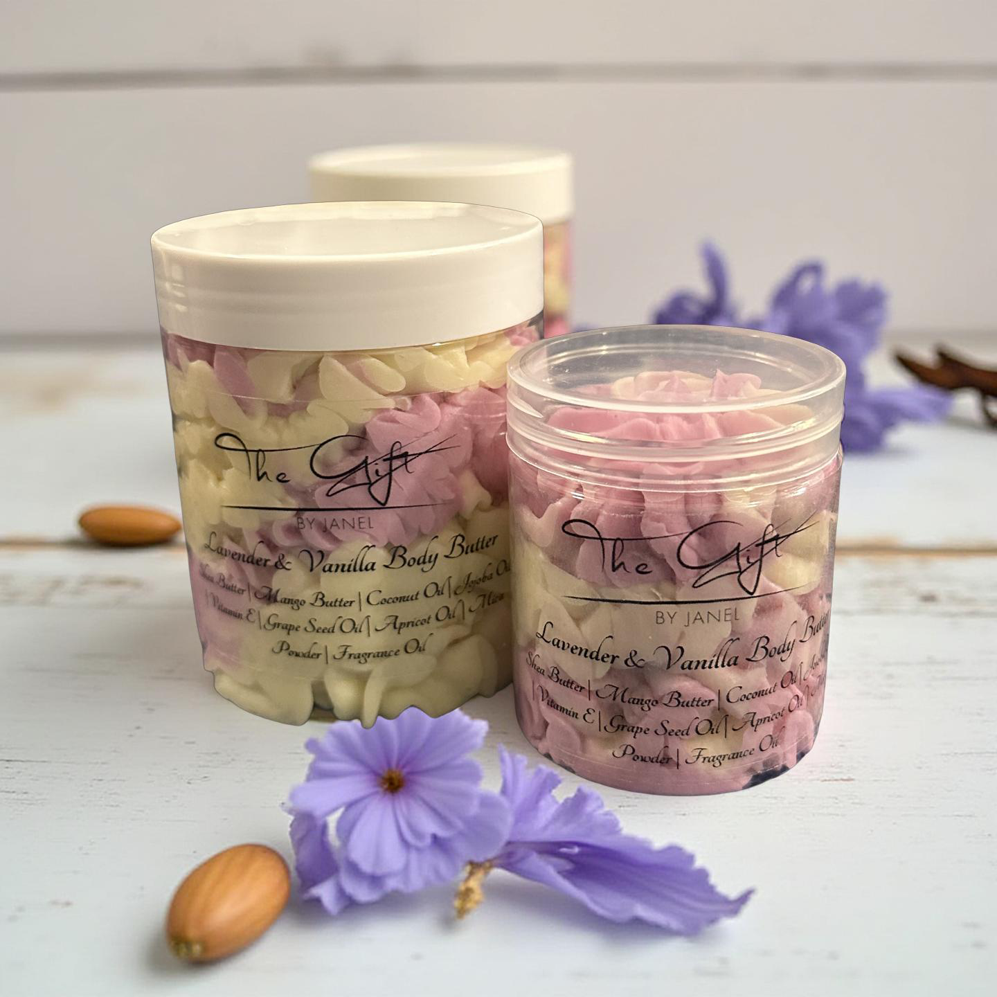 Two jars of lavender and vanilla body butter with flowers and nuts on a light surface.