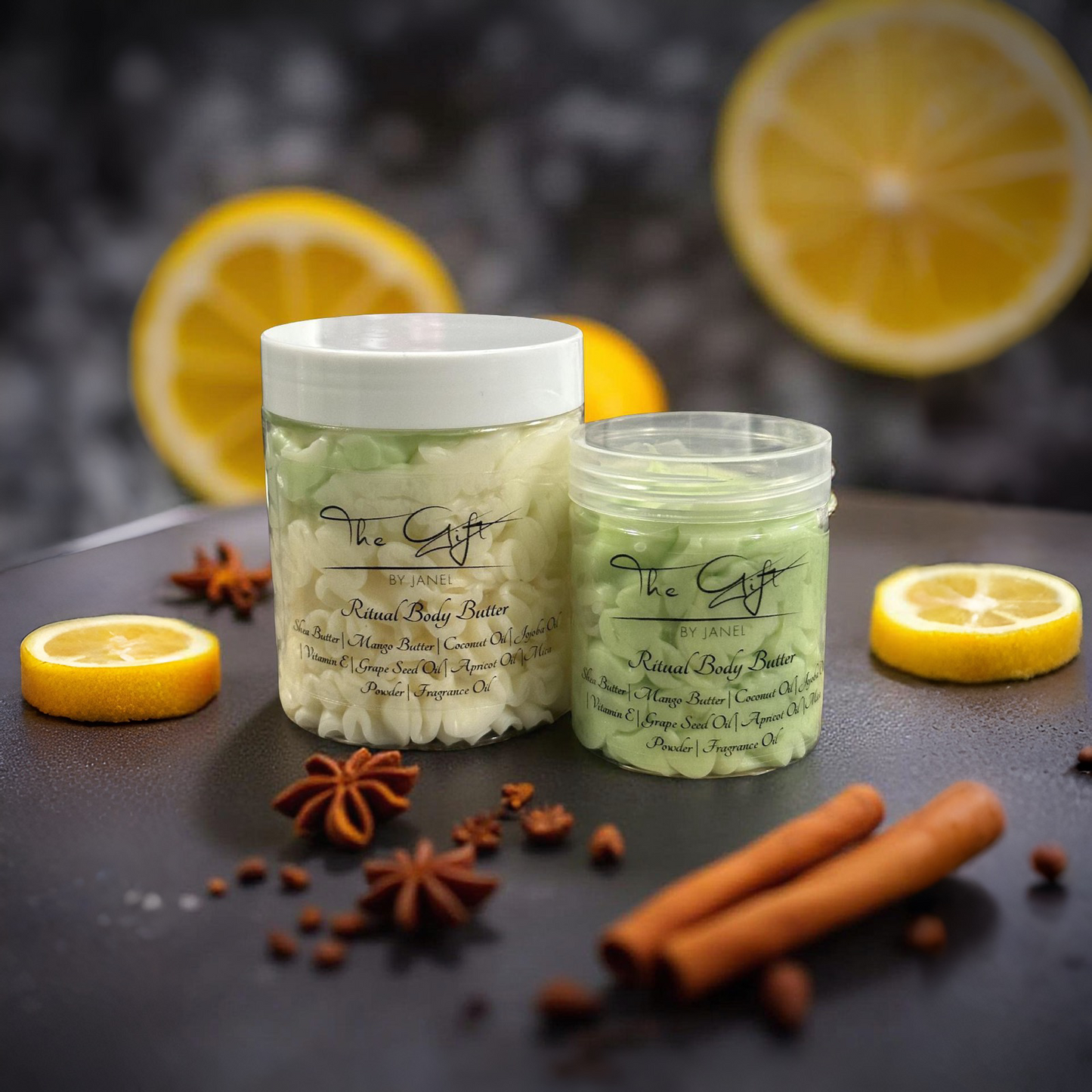 Two jars of body butter with lemons and spices on a dark surface