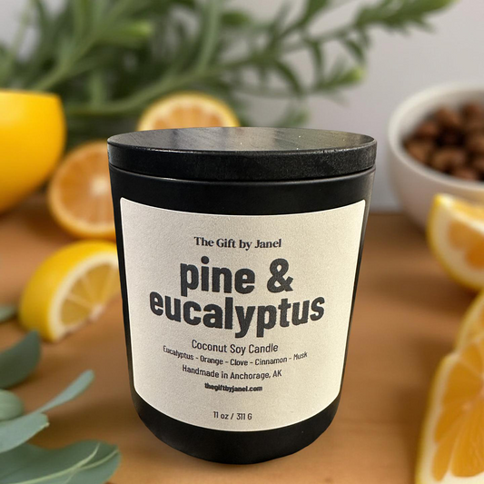 Candle labeled 'pine & eucalyptus' on a wooden surface with lemons and greenery.