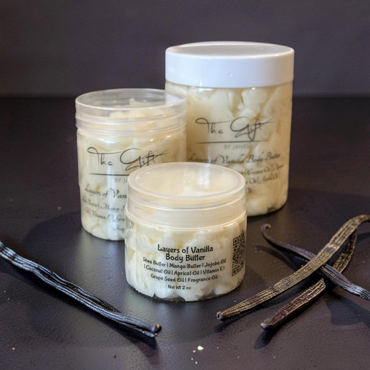 Three containers of 'Layers of Vanilla' body butter on a dark surface with vanilla beans.