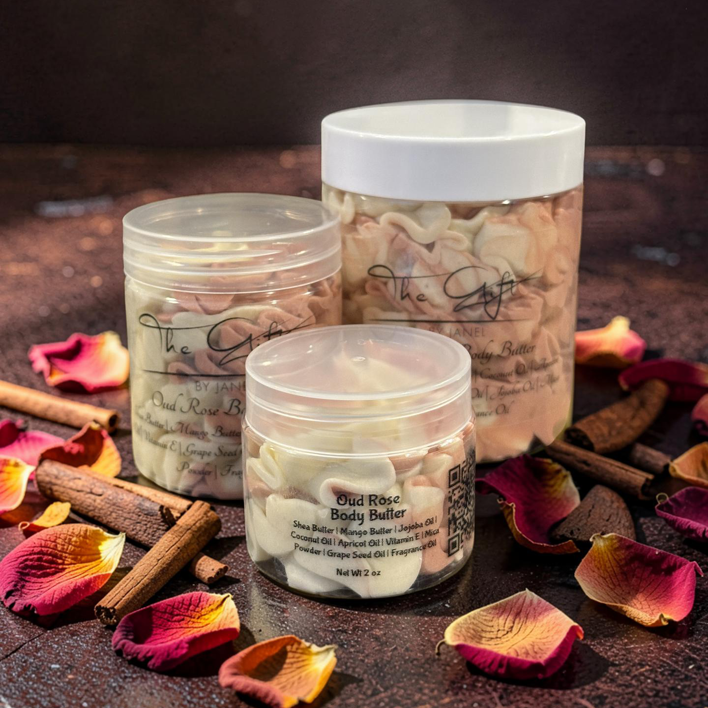 Three body buffers with labels on a dark surface with oud sticks and rose petals.
