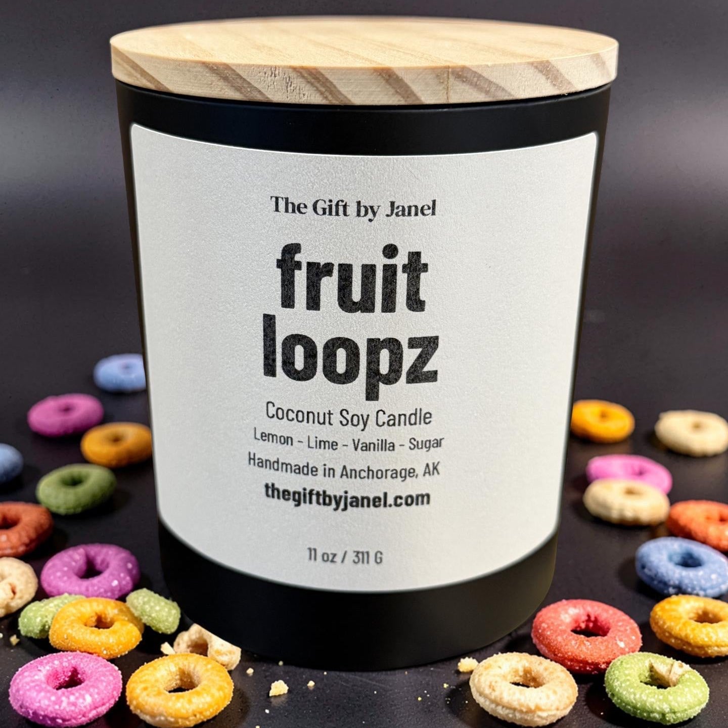 Candle labeled 'fruit loopz' with colorful donut-shaped candles around on a dark background