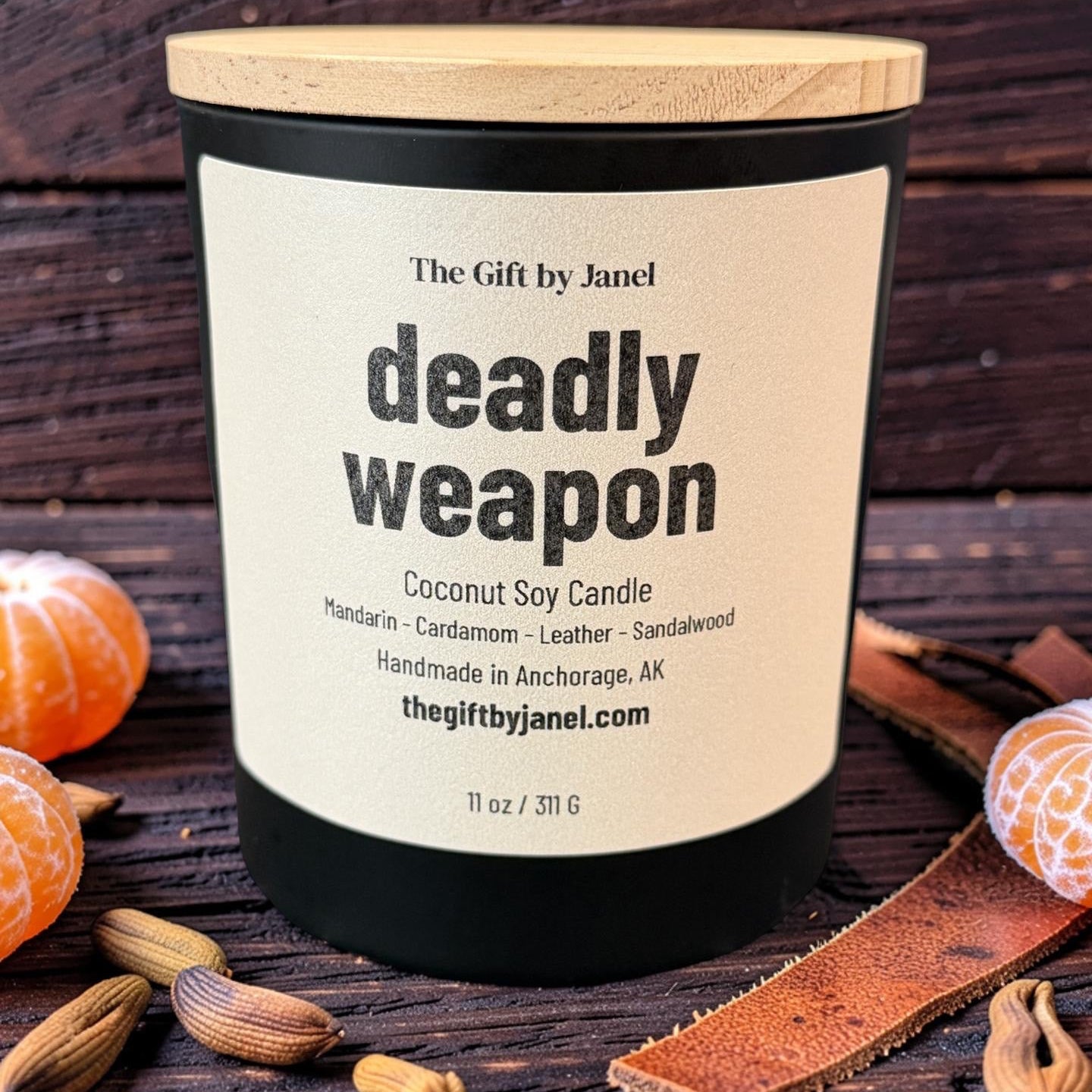 Candle labeled 'deadly weapon' on a wooden surface with spices and oranges.