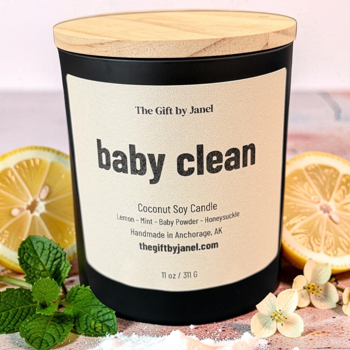 Coconut soy candle labeled 'baby clean' with lemons and mint leaves on a wooden surface.