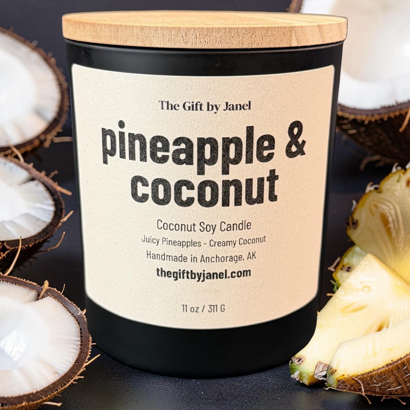 Candle labeled 'Pineapple & Coconut' with a wooden lid, surrounded by coconut halves and a pineapple on a dark background.